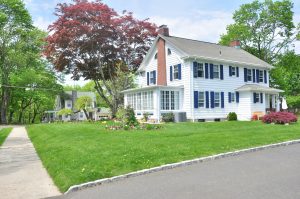 white house with neat lawn and red tree